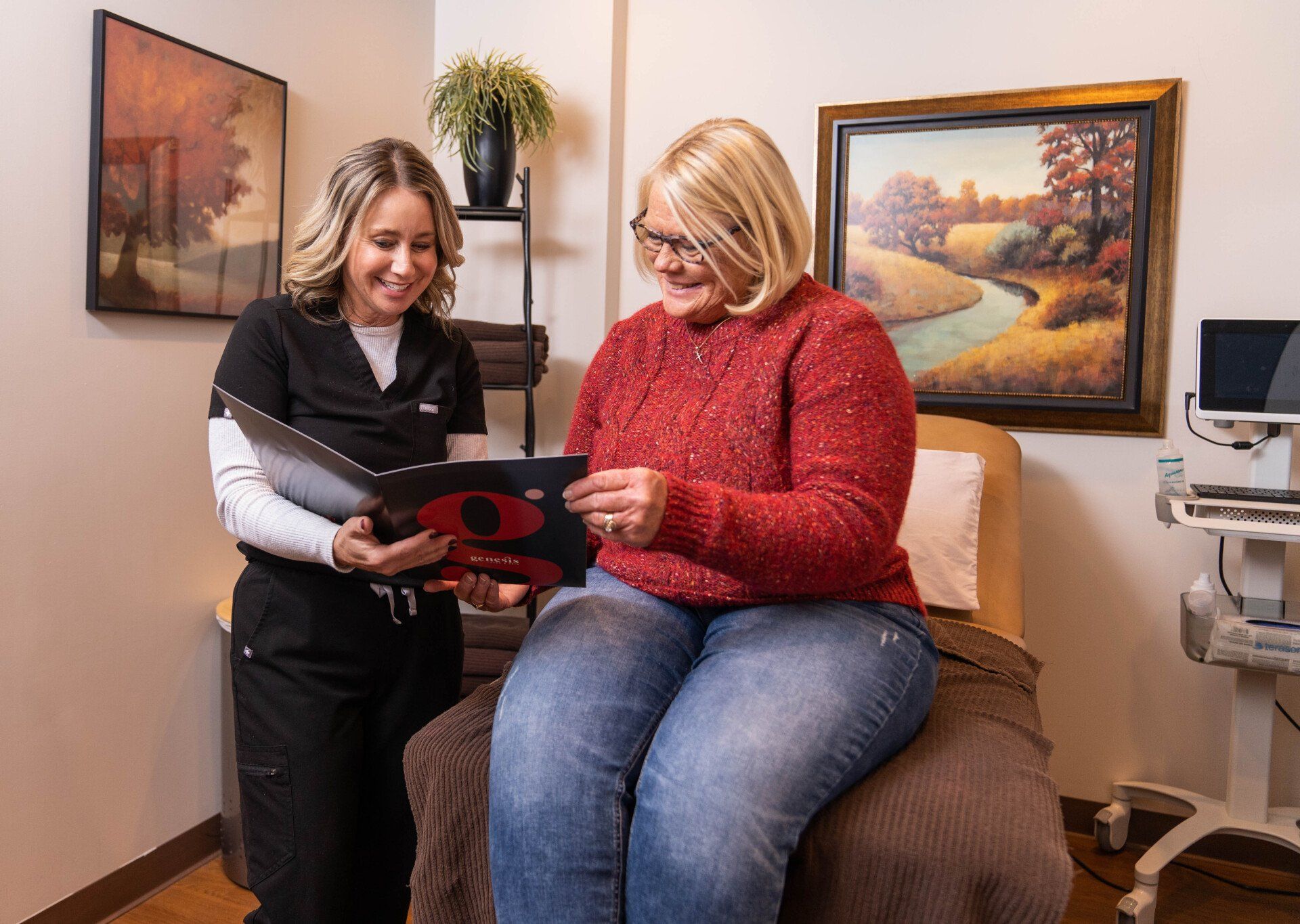 A nurse is talking to a patient who is sitting on a bed.