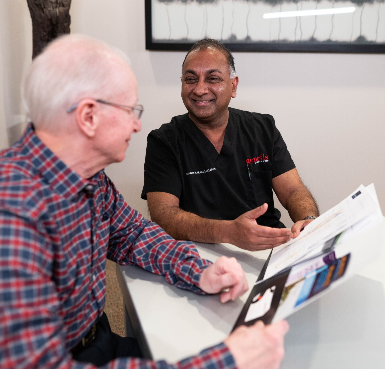 Two men are sitting at a table talking to each other