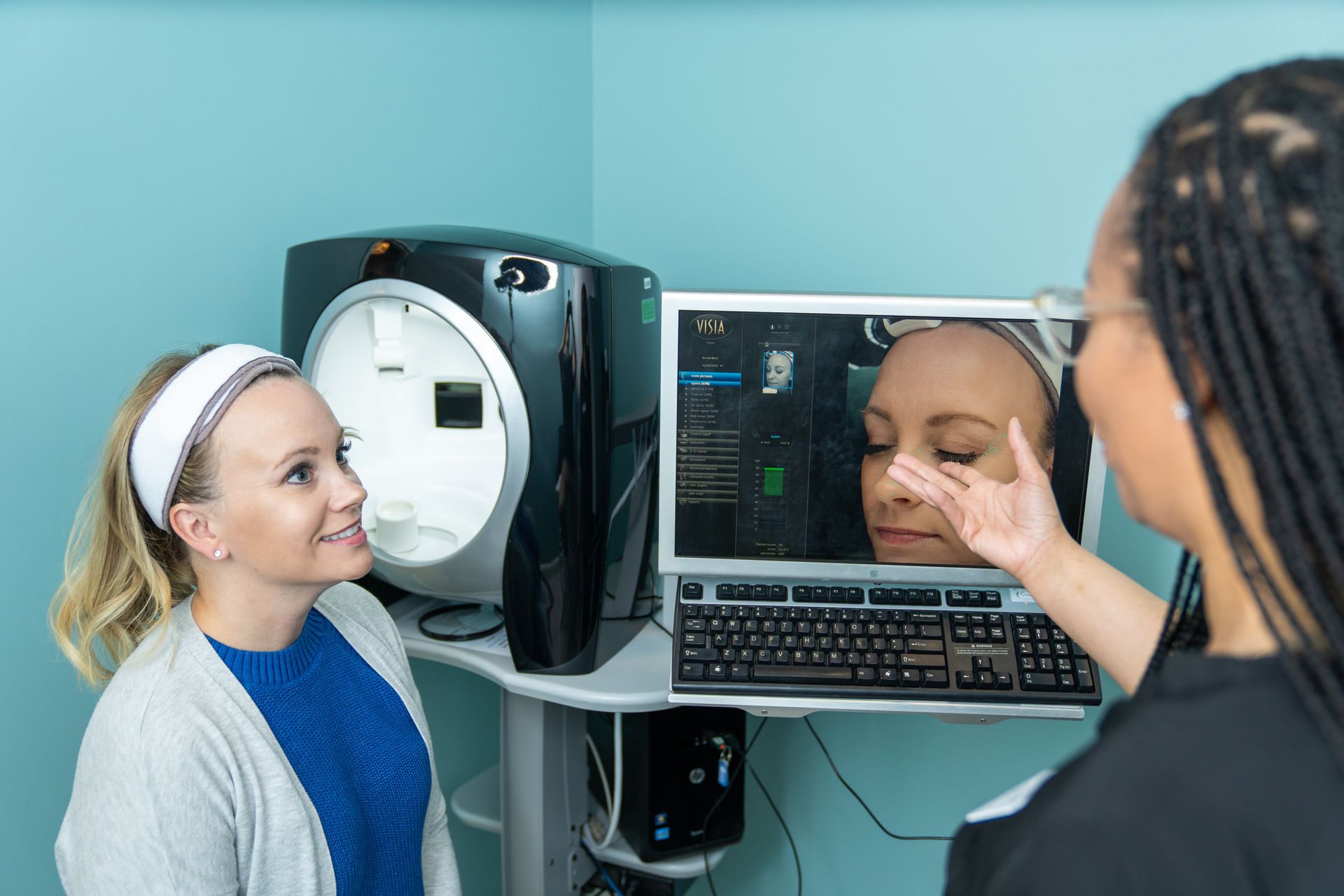 Two women are looking at their faces in a mirror.