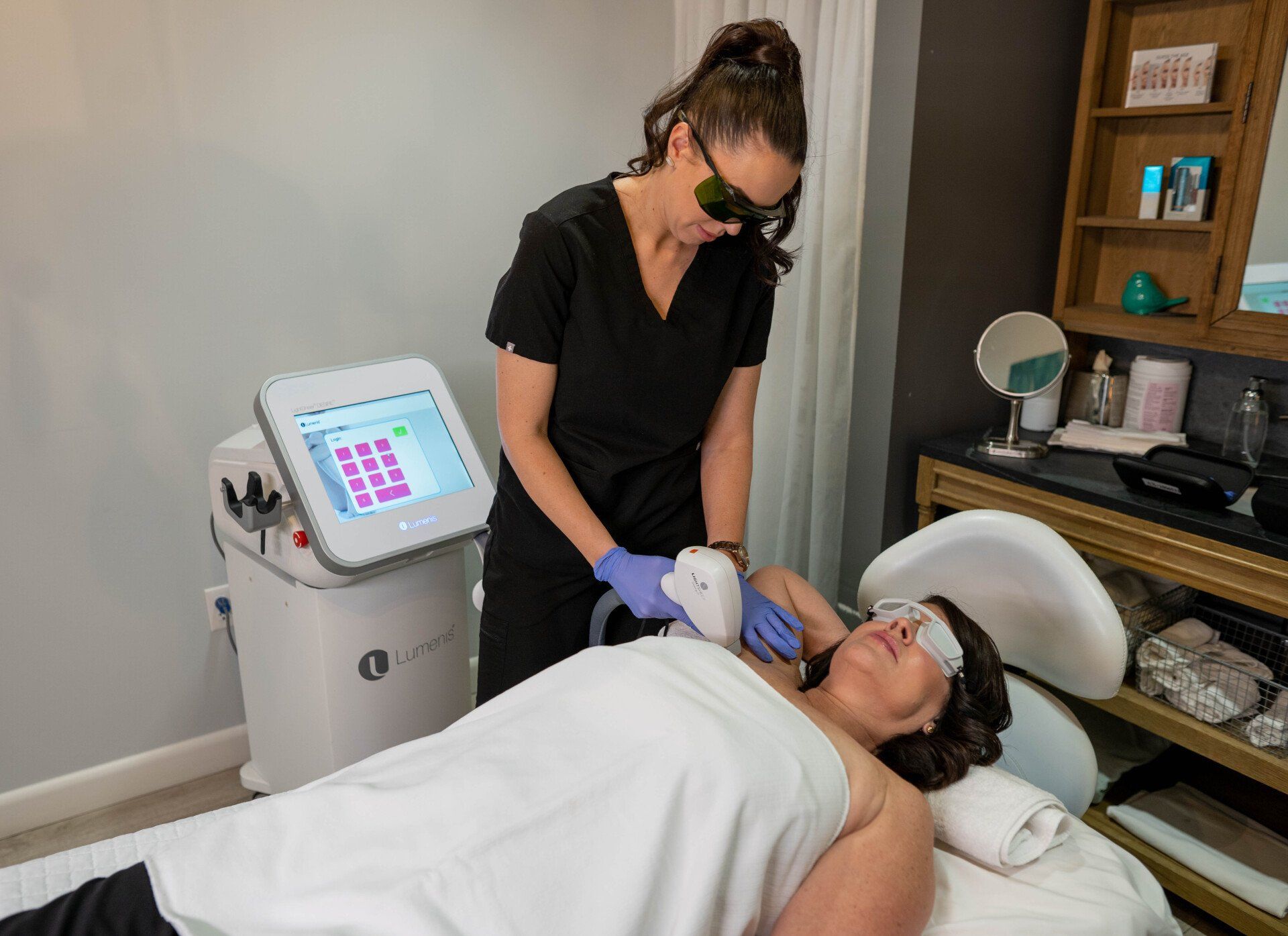 A woman is laying on a bed getting a laser hair removal treatment.