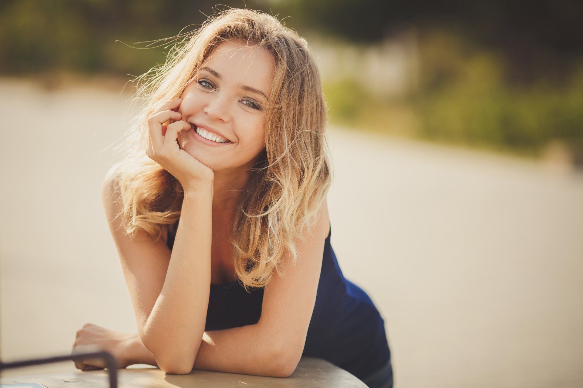 A woman is laying on the ground with her hand on her chin and smiling.