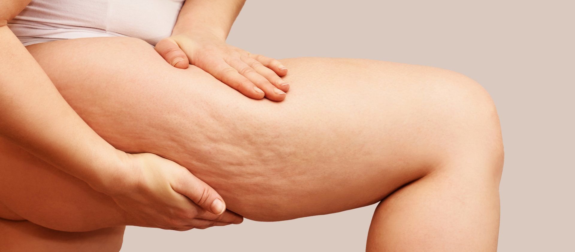 A woman is holding her thigh with her hands.