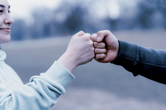 A man and a woman are putting their fists together.