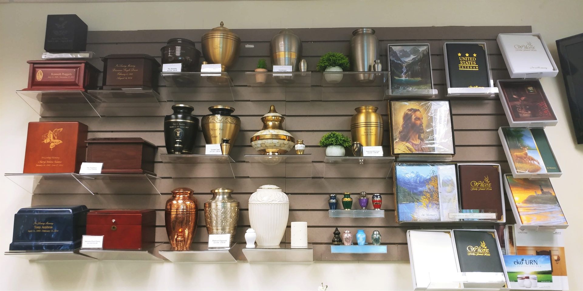 Shelves of decorative urns, vases, and small boxes displayed against a gray wall.