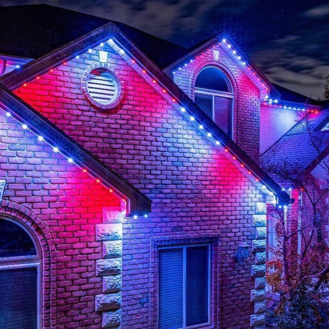 House roofline lit with red, blue, and purple holiday lights at night