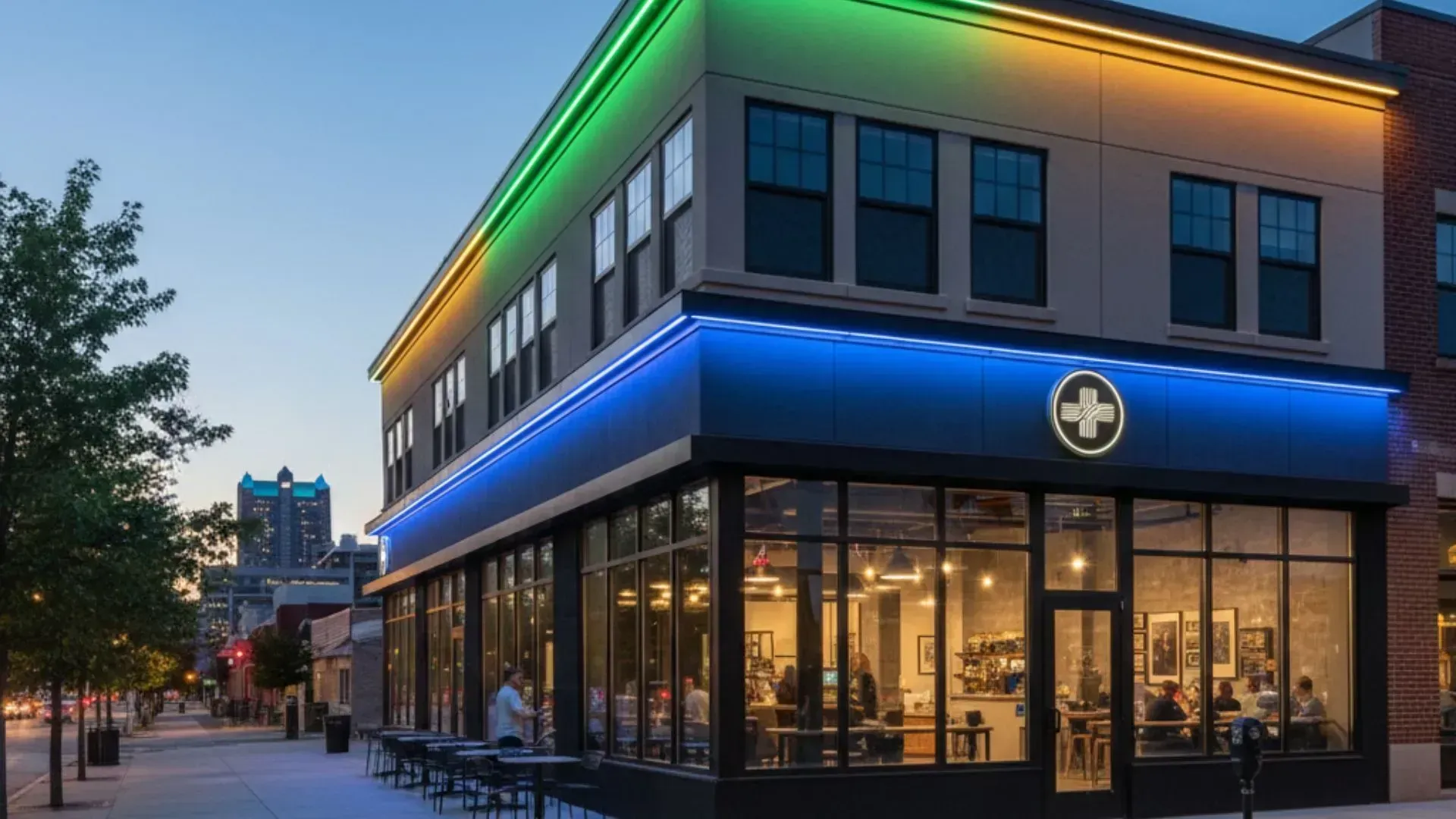Corner building with neon green and blue trim, glass storefronts, and warm interior lights at dusk.