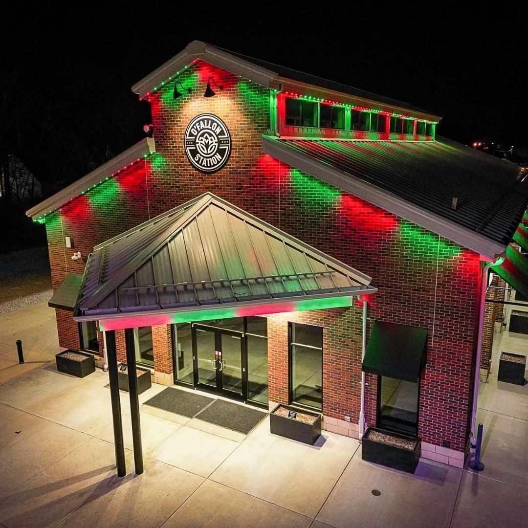 Brick building entrance lit with red and green holiday lights at night