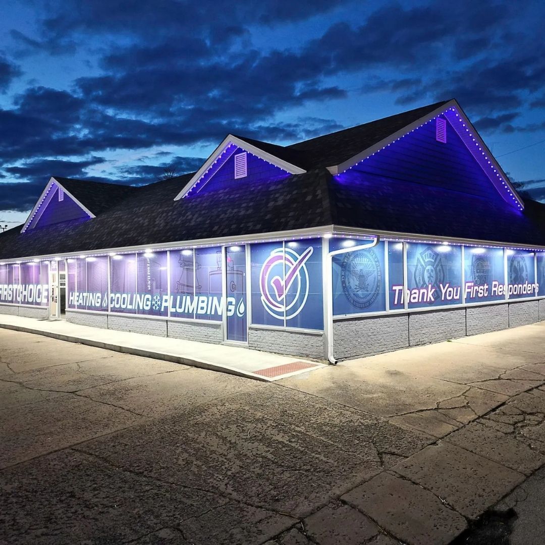 Blue-lit plumbing company building at night with illuminated banners and cracked parking lot