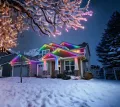 House decorated with rainbow Christmas lights in a snowy yard at dusk
