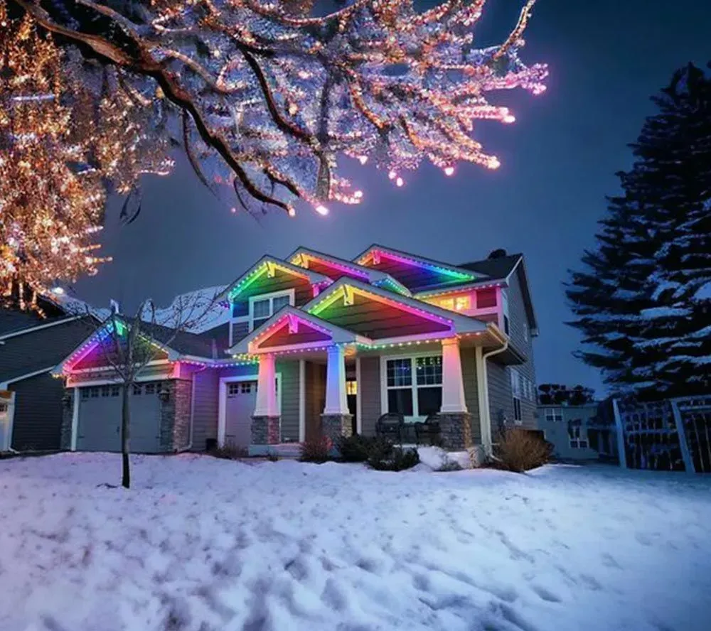 House decorated with rainbow Christmas lights in a snowy yard at dusk