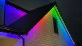 House roofline outlined with colorful rainbow holiday lights at night