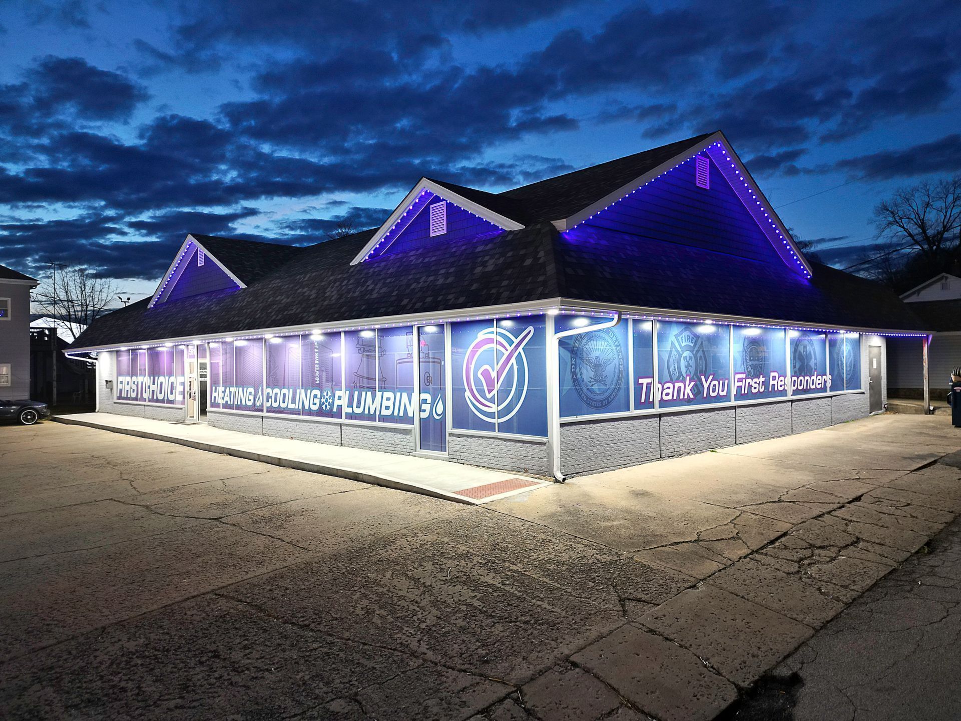 Purple-lit storefront at dusk with large holiday window graphics and snowy ground