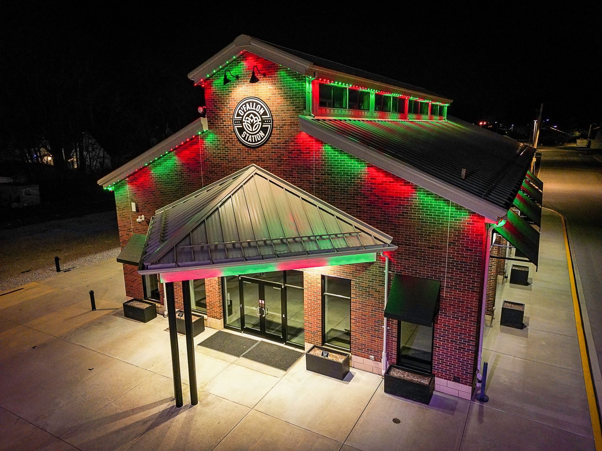 Decorated building at night with red and green holiday lights and a snowy ground