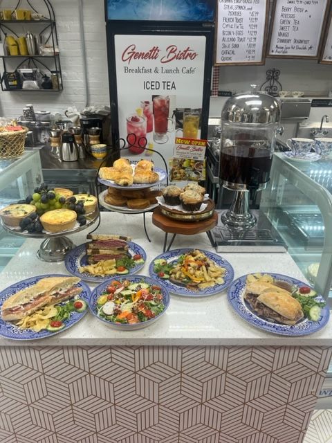 Dessert and snack display case with pastries, fruit, sandwiches, and iced tea in a café.