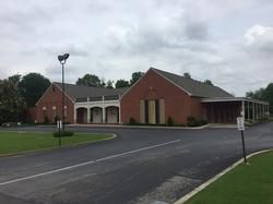 Brick building with arched entrance and covered driveway on a cloudy day
