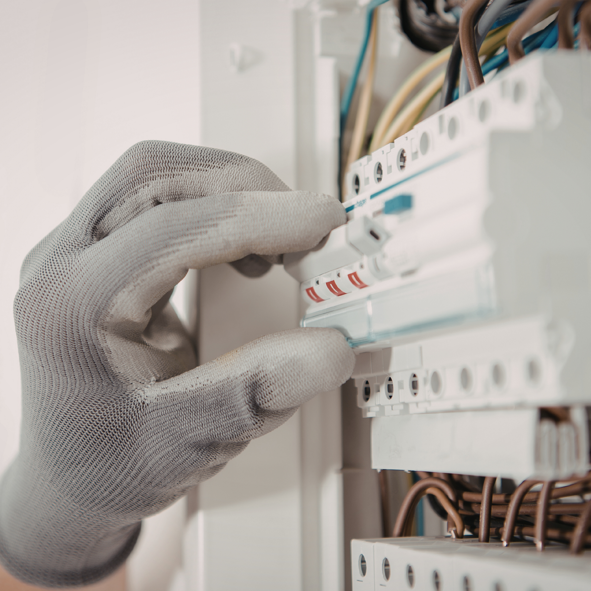 Gloved hand adjusting a white circuit breaker in an electrical panel