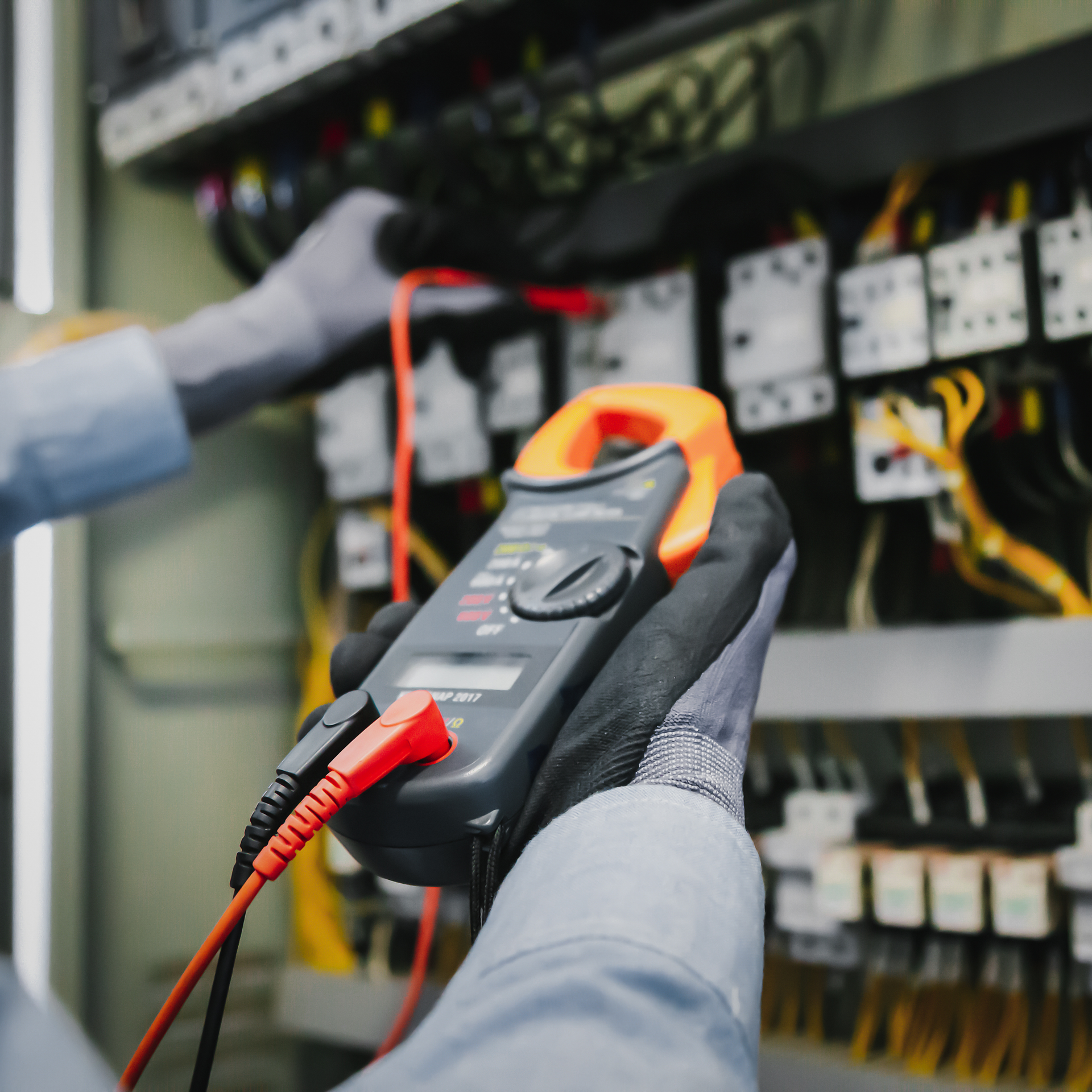 Electrician inspecting an open circuit breaker panel in a white wall