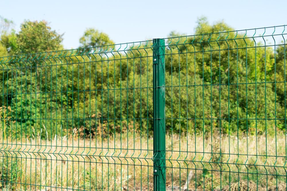 Green Wire Fence in Front of Lush Green Trees Against a Clear Blue Sky — Keith Dellit Rural Fencing in Yandina Creek, QLD
