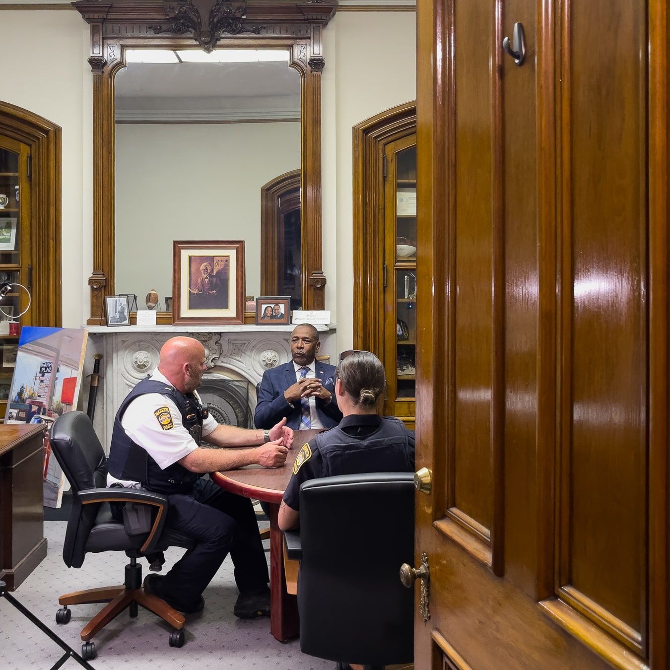 Mayor Dough Franklin and city police officers sitting around a table, talking.