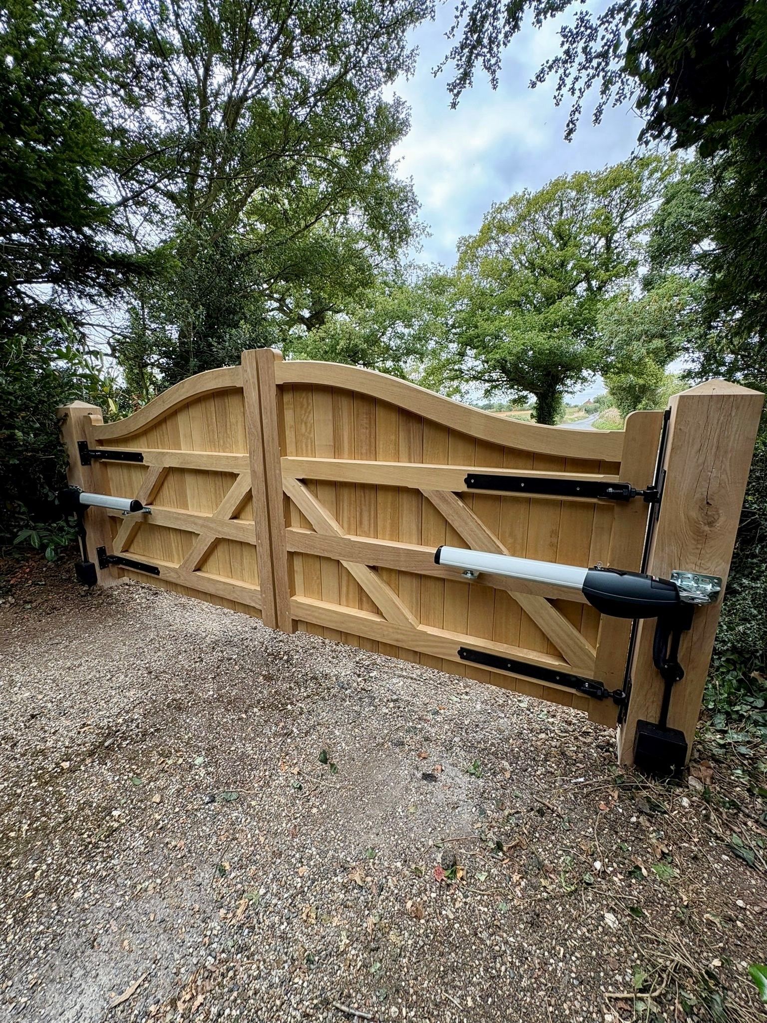 Bespoke made timber Electric Gate with trees all around it 
