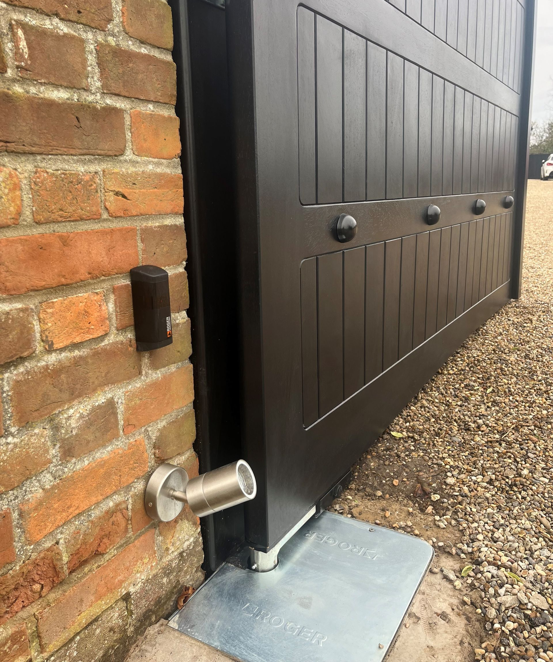 close up of black wooden Electric Gate attached to brick column