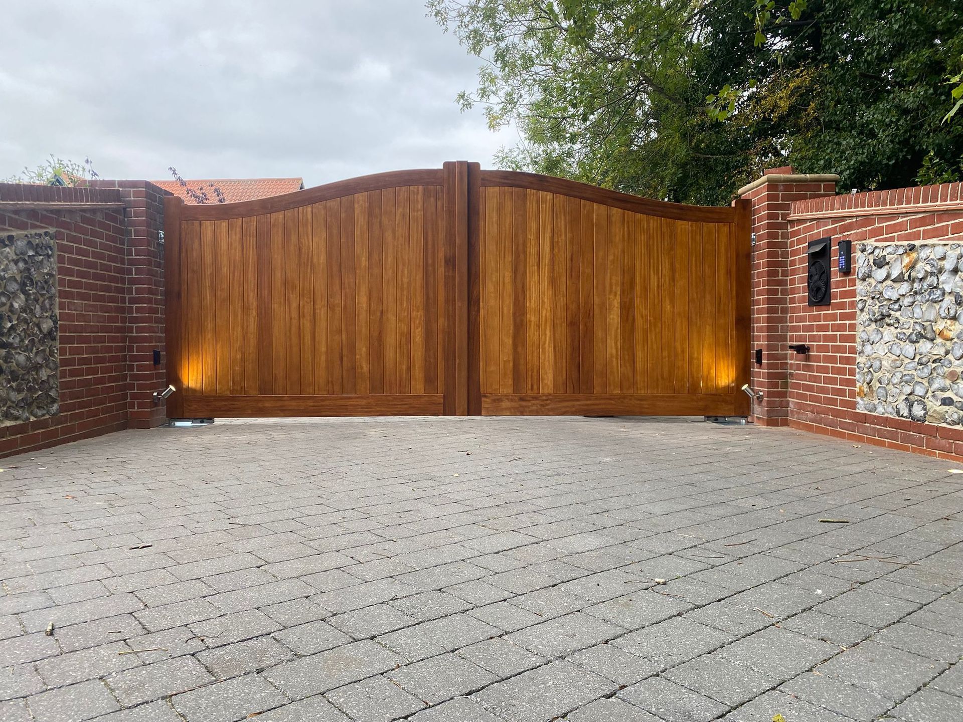 A brand new installed Electric gate that is closed across a high-end driveway with lights either sid