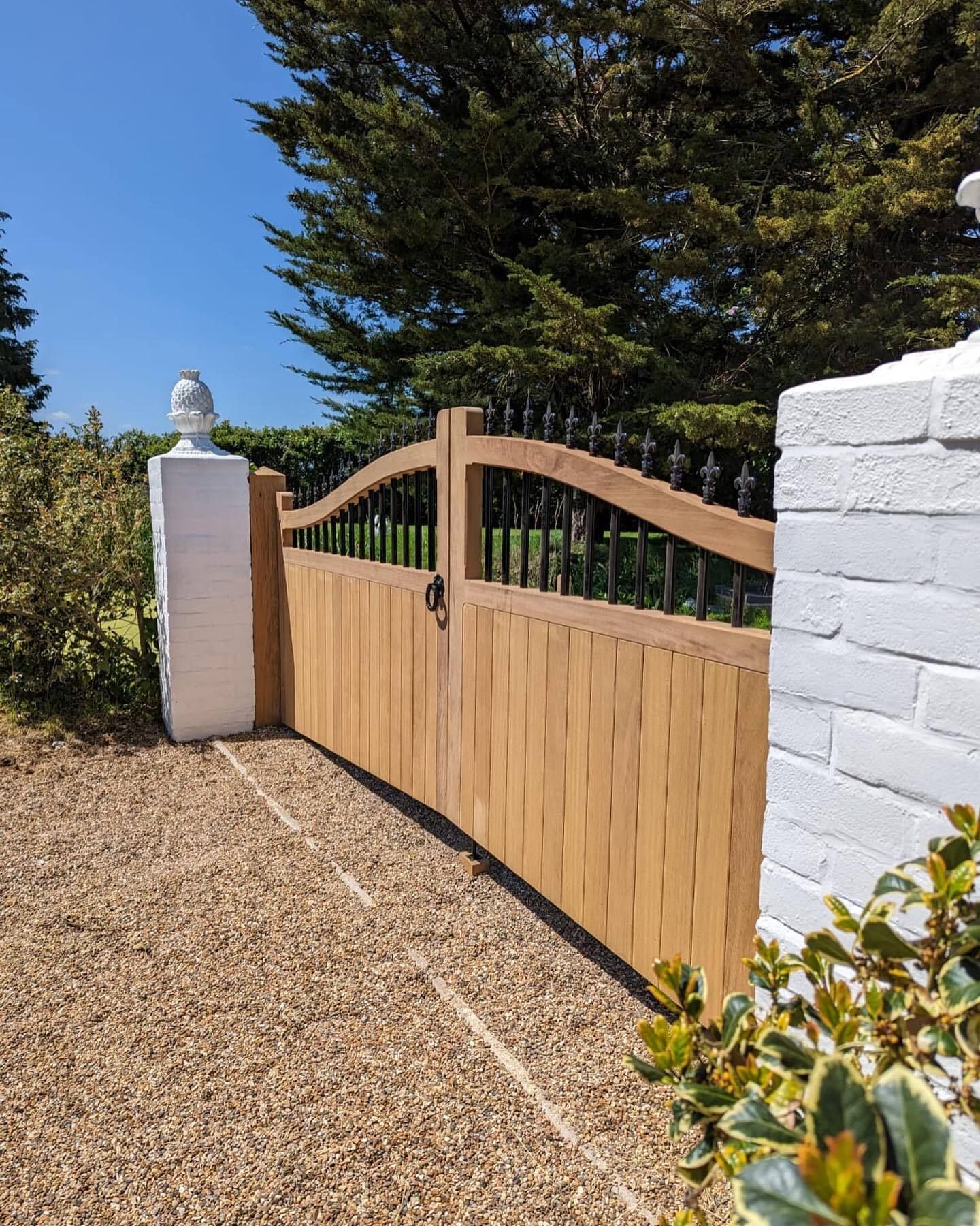 A wooden gate with metal bars is sitting in front of a brick house.