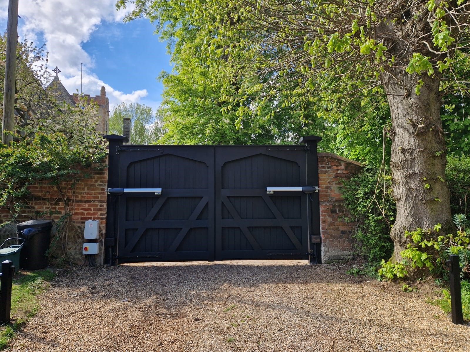 Black wooden Electric Gate with wall either side of it 