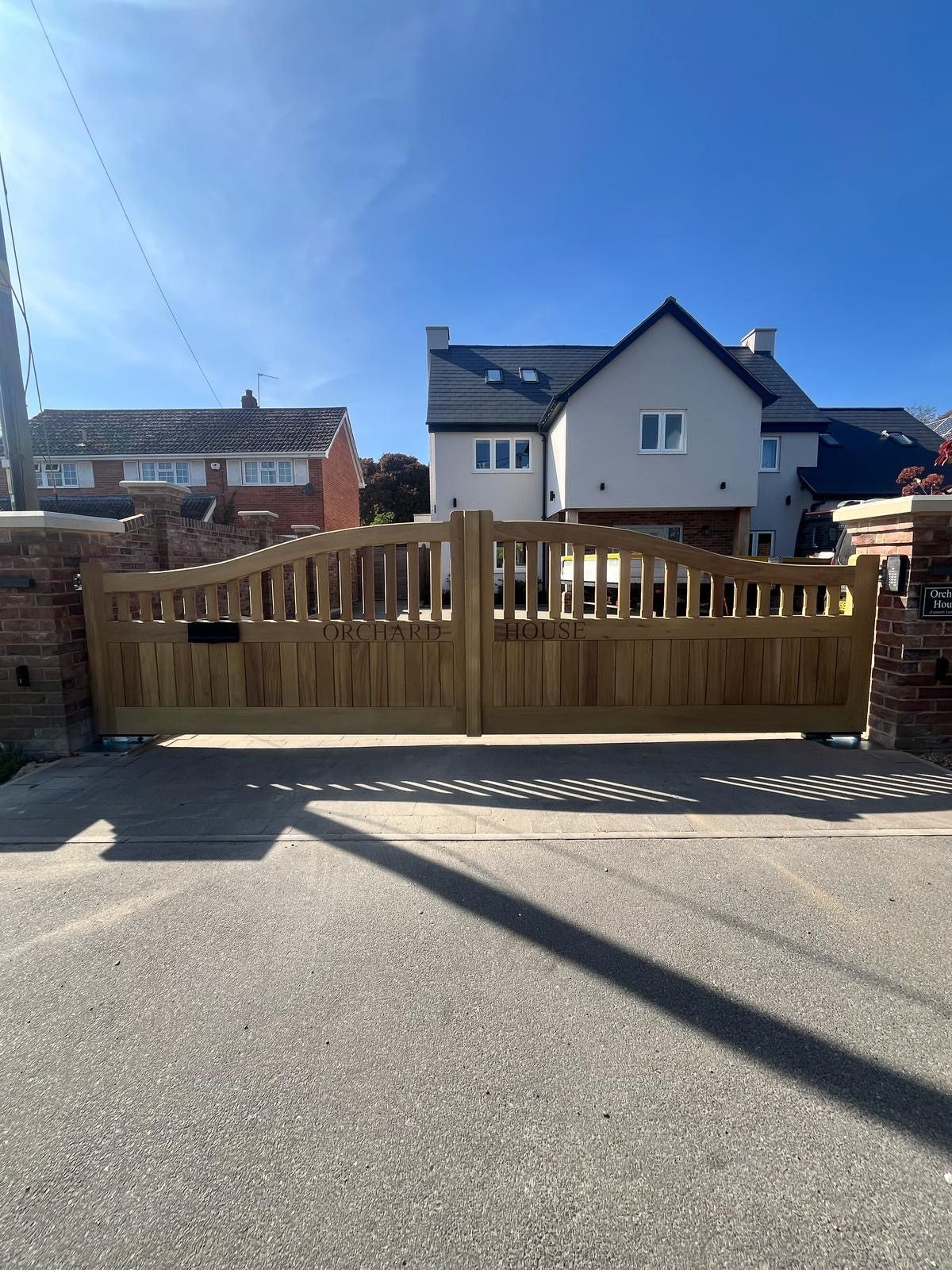 Wooden driveway electric gate in front of a house on a sunny street