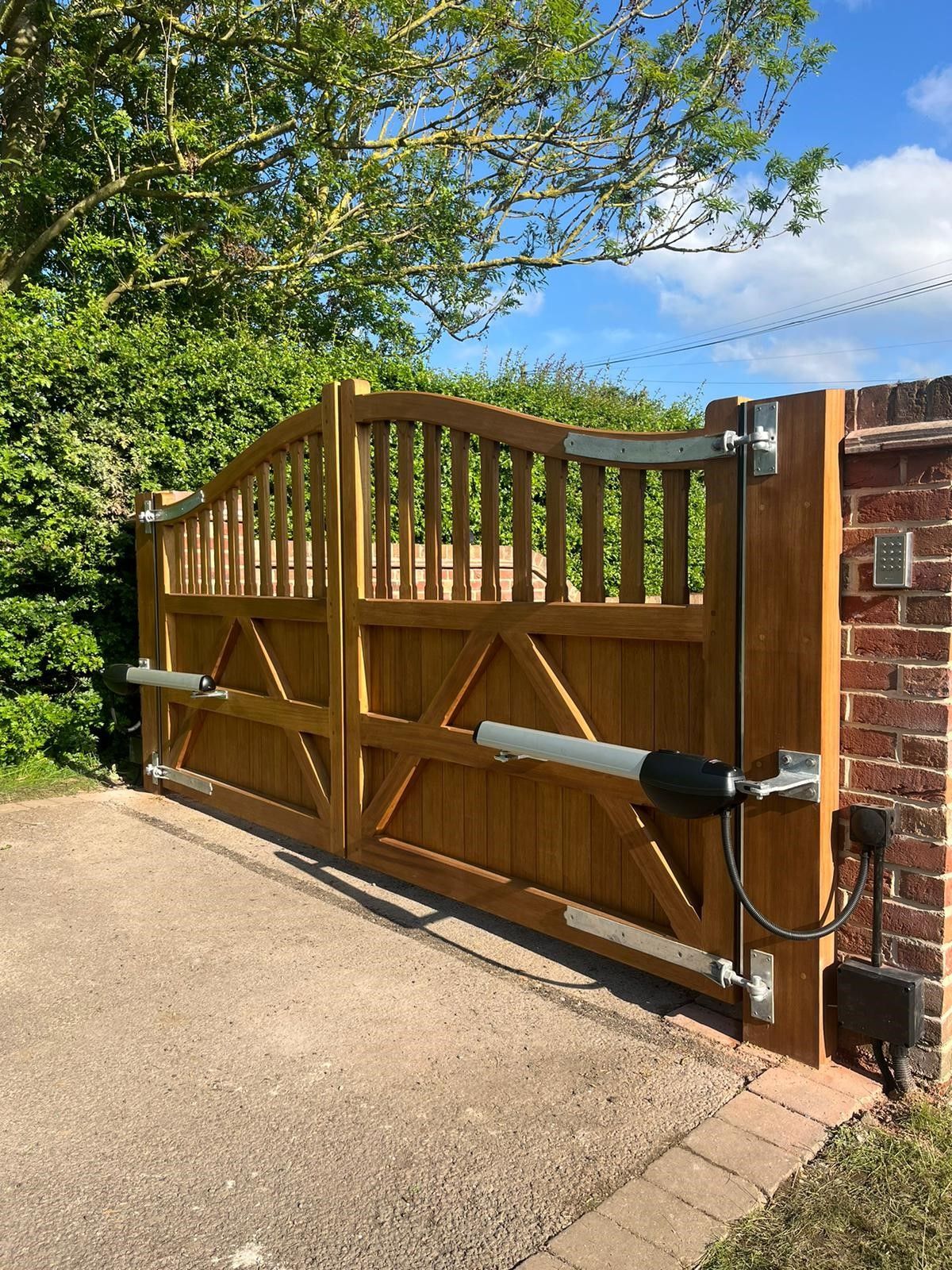 Electric Gate made bespoke size from timber with a tree above it and blue sky in the background 