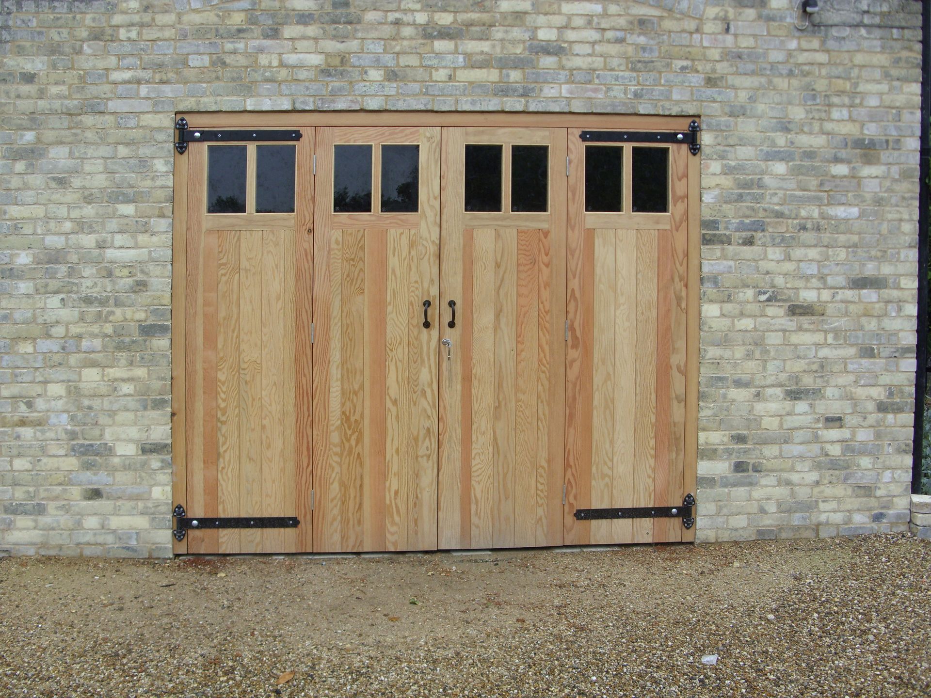 Wooden double doors with small windows set in a stone wall.