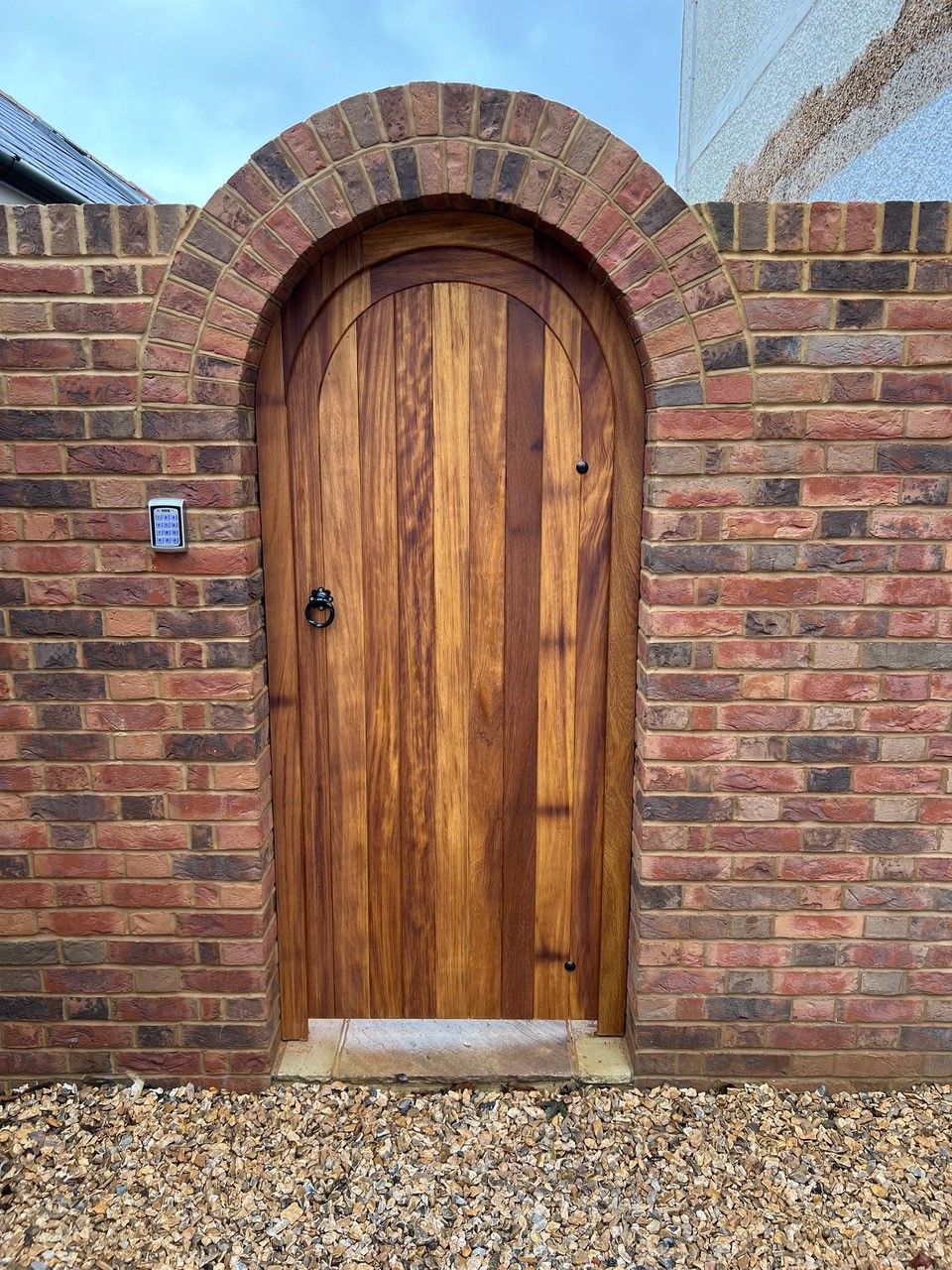 close up of timber backgate with surrounding brick wall and arch 
