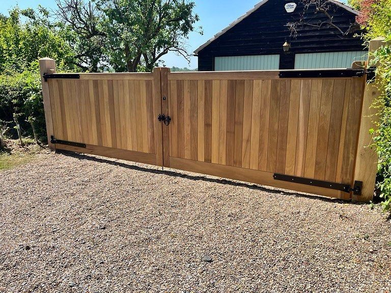 Wooden sliding driveway gate beside a gravel driveway and trees