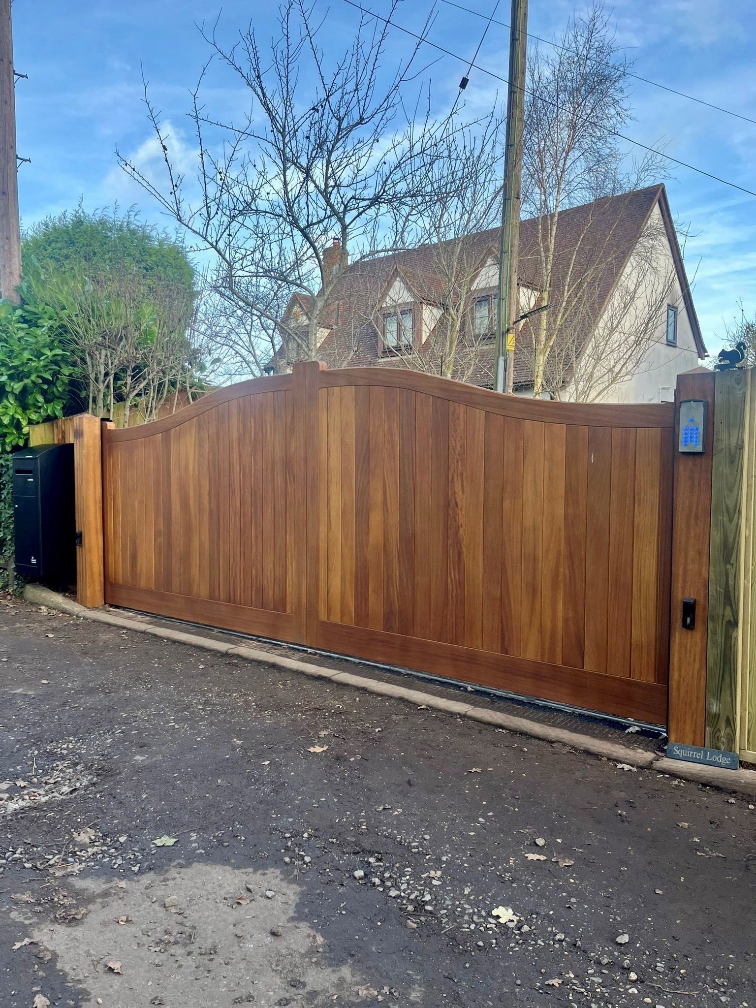 bespoke made timber Electric Gate with house in background 