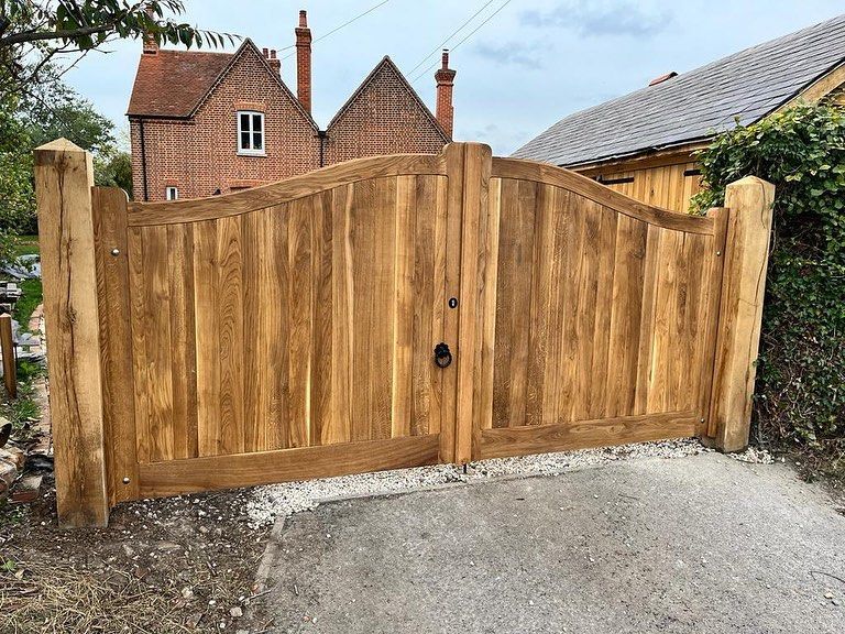 bespoke made timber Electric Gate with bushes either side and house in background