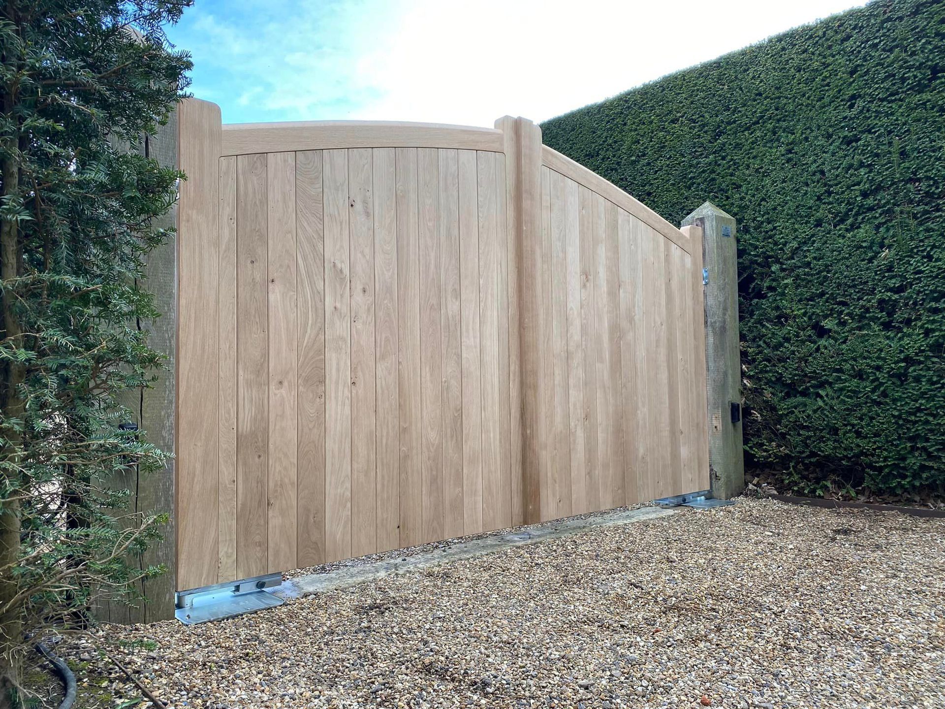close up of bespoke-made timber Electric Gate with immaculate hedge beside it 
