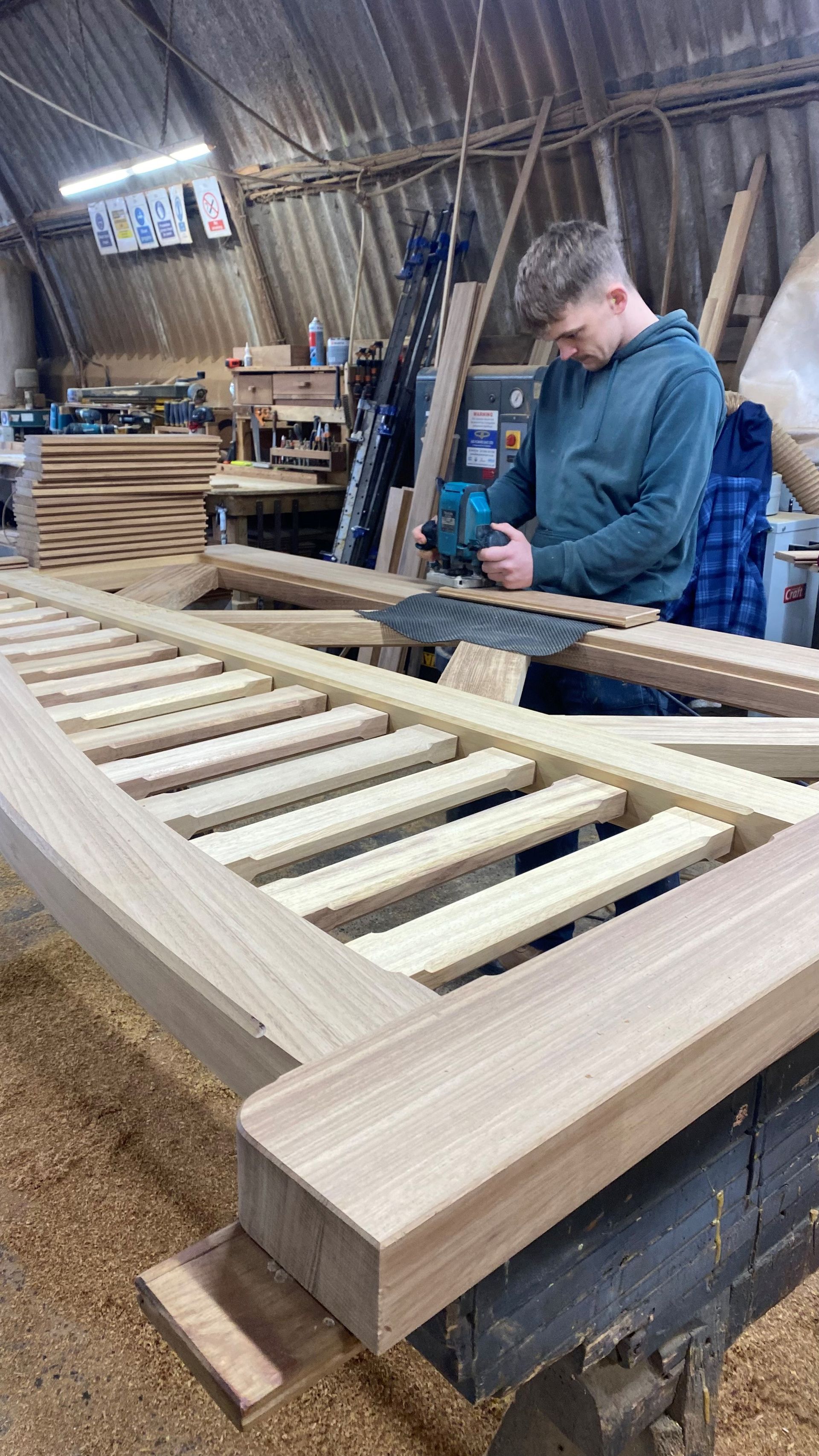 Woodworker sanding a wooden frame on a bench in a workshop