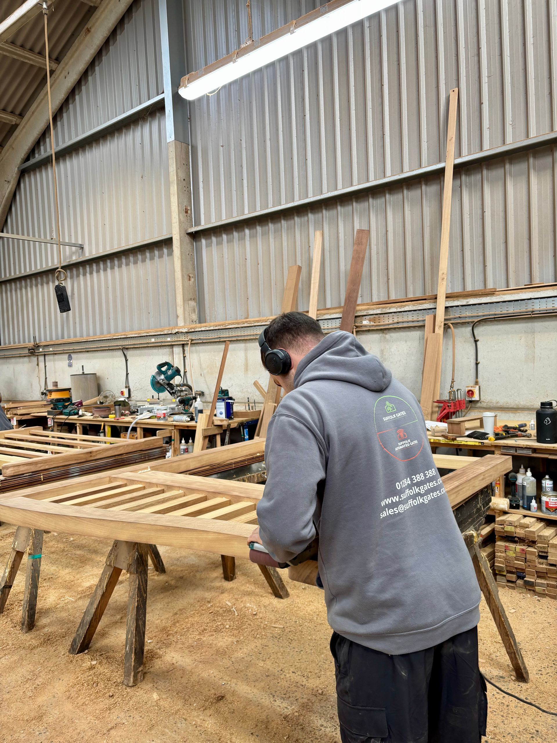 Person in a gray hoodie working on a large wooden frame in a workshop shed