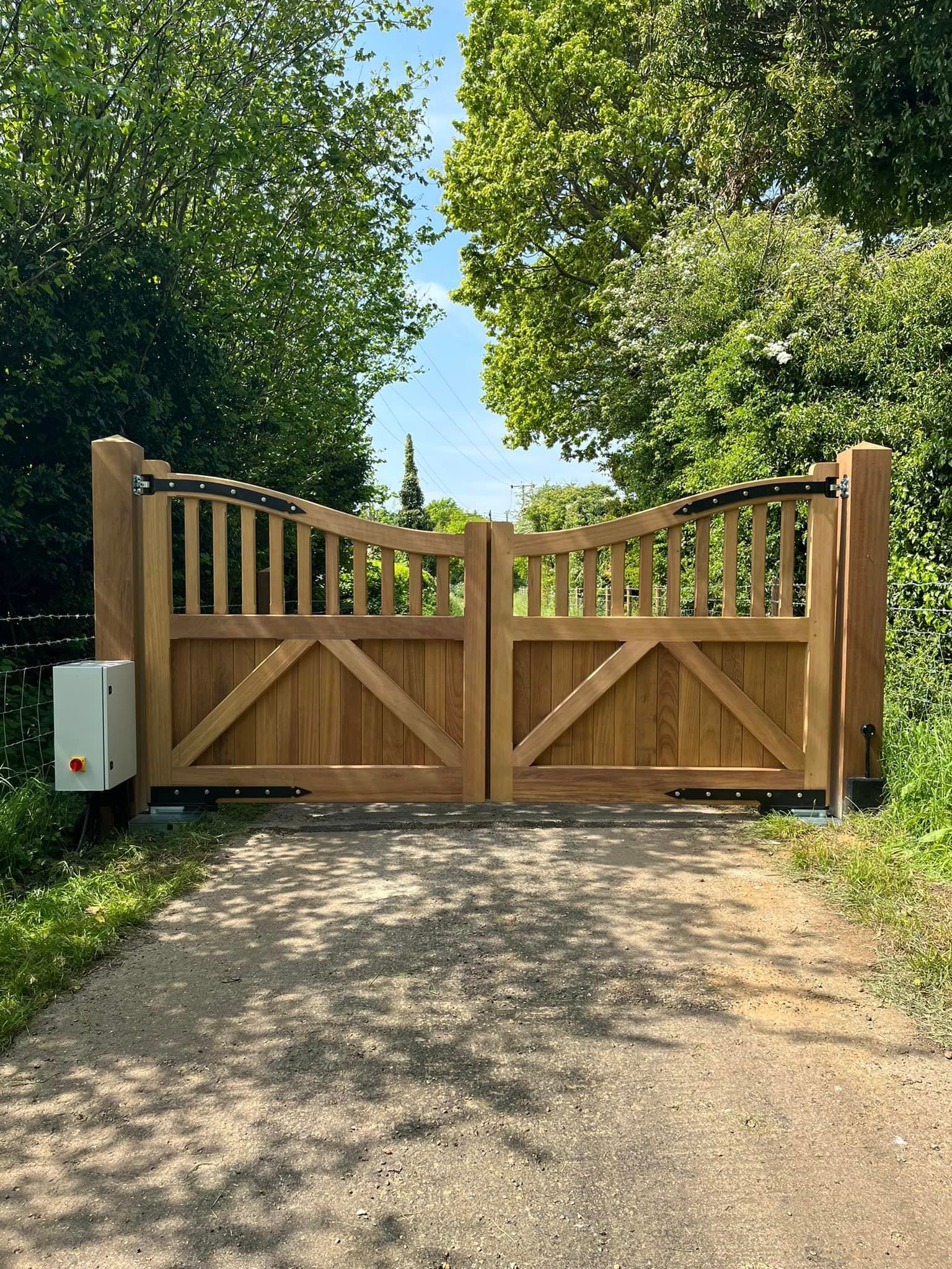 Wooden driveway gate between trees on a sunny rural lane