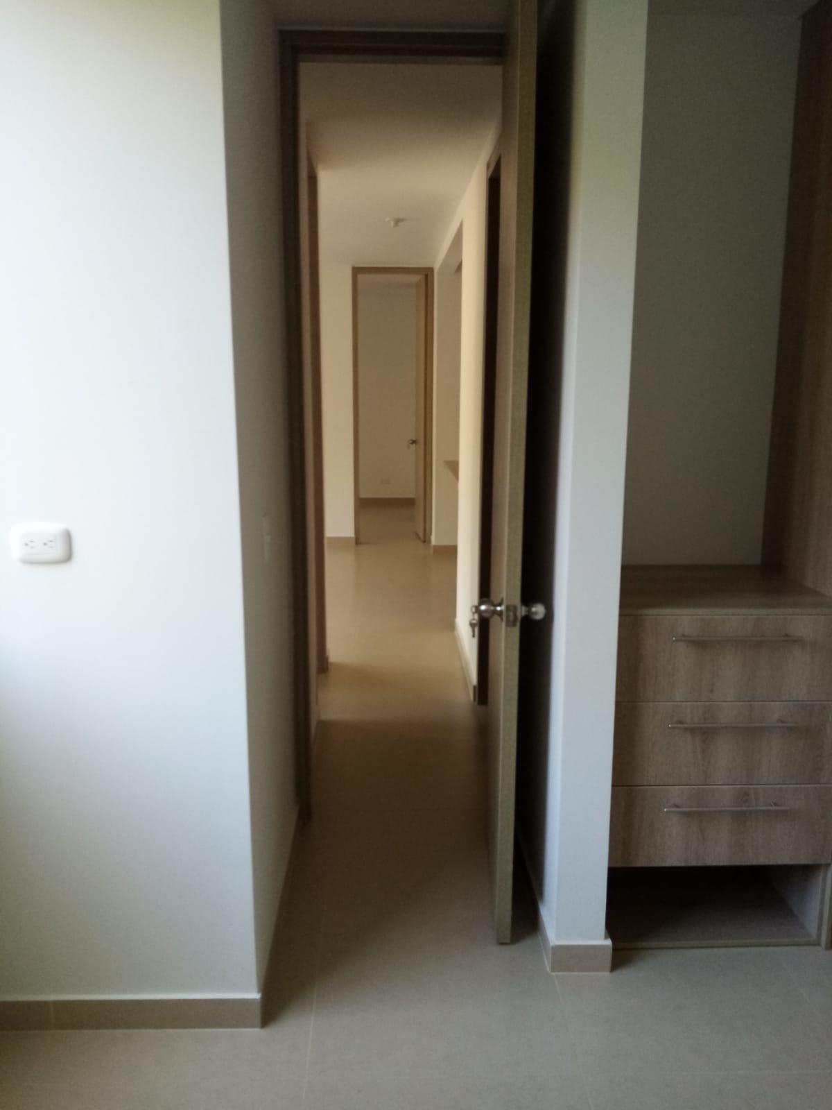 Un dormitorio con vestidor y puerta que da a un pasillo.