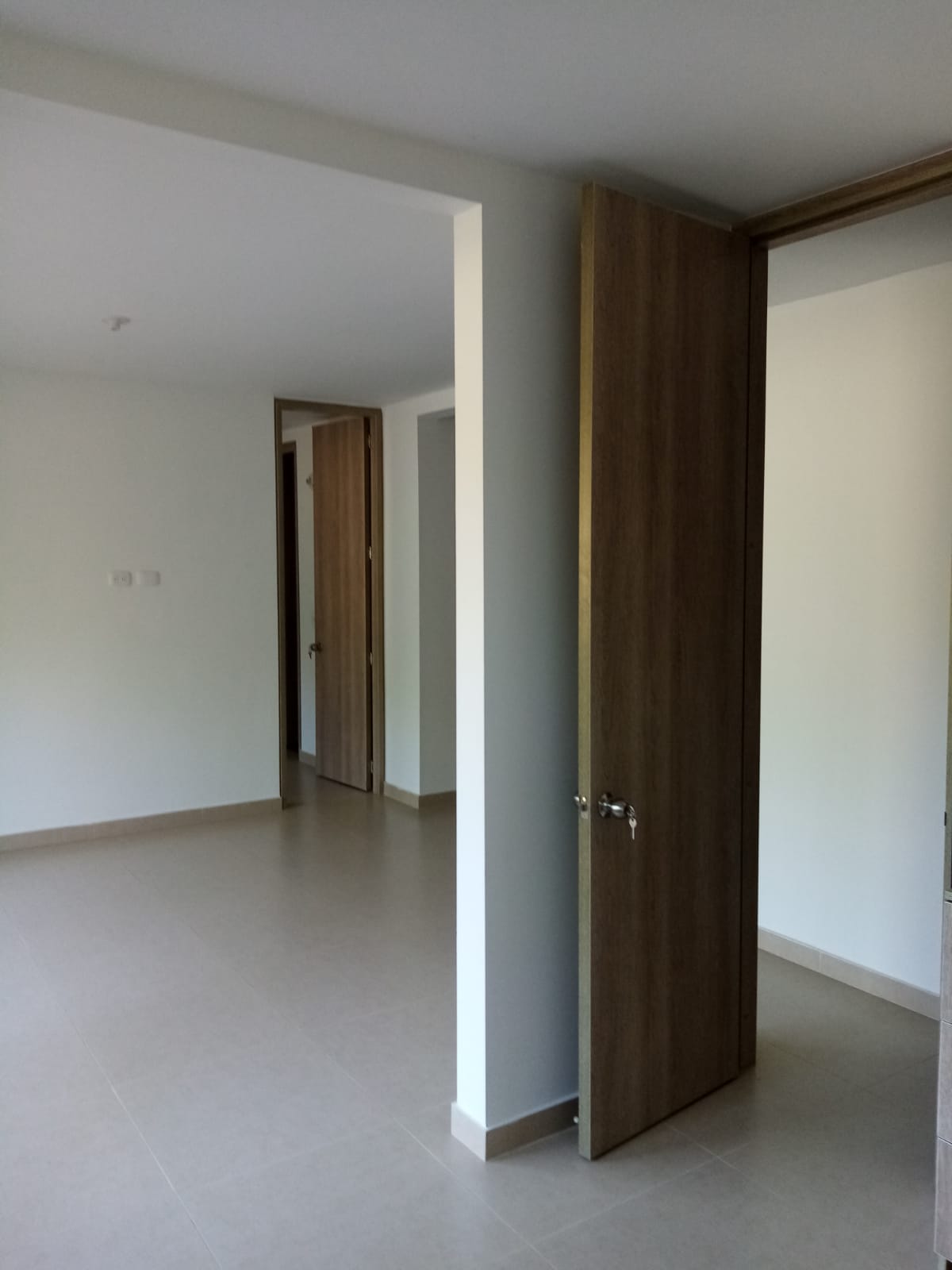 Una habitación vacía con una puerta de madera y paredes blancas