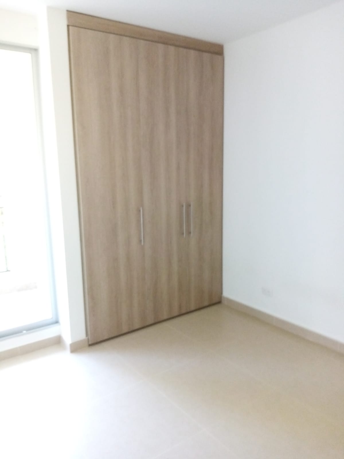 Una habitación vacía con un gran armario de madera y una ventana.