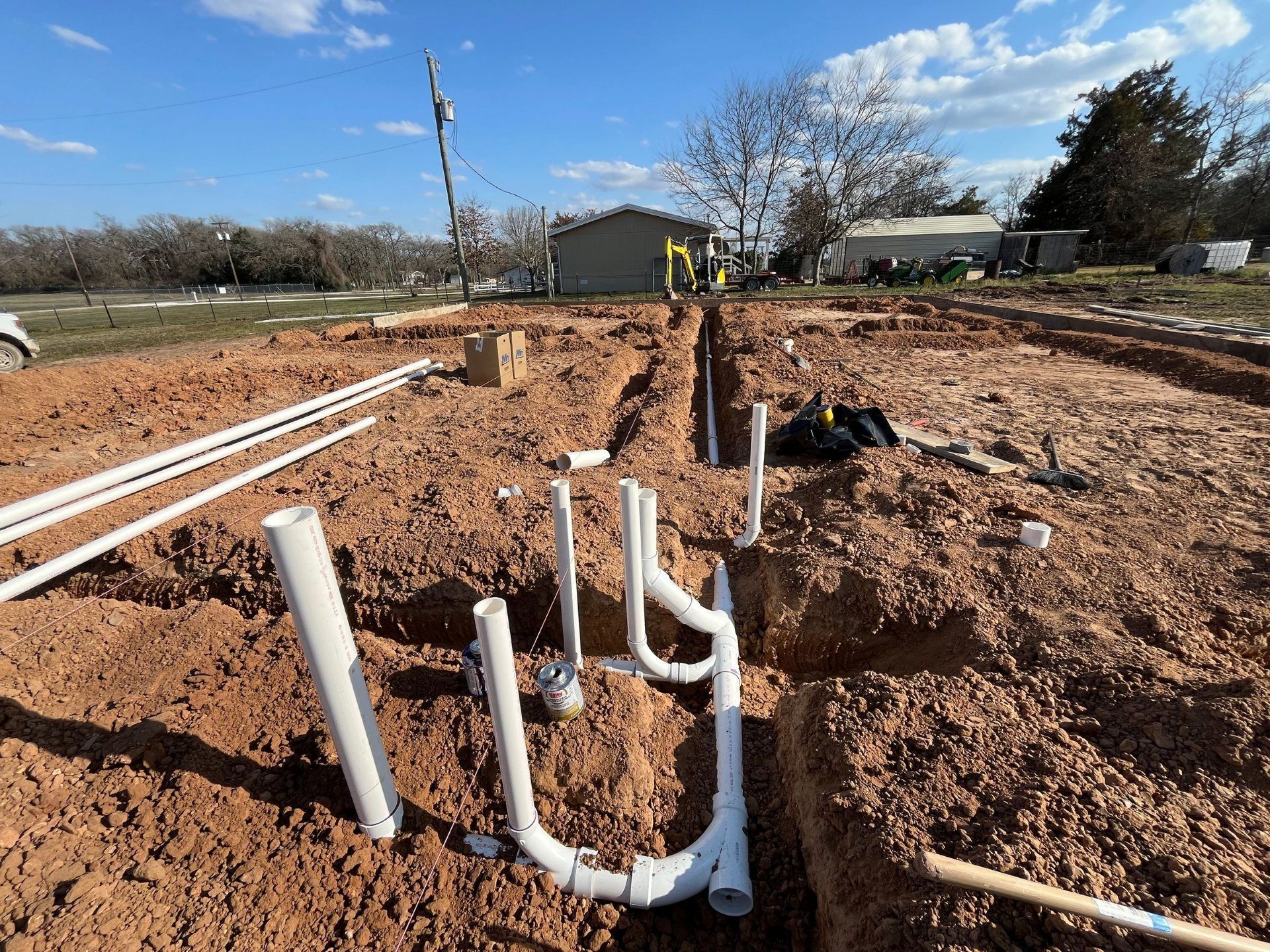 Construction site with PVC pipes in trenches, preparing for plumbing installation.