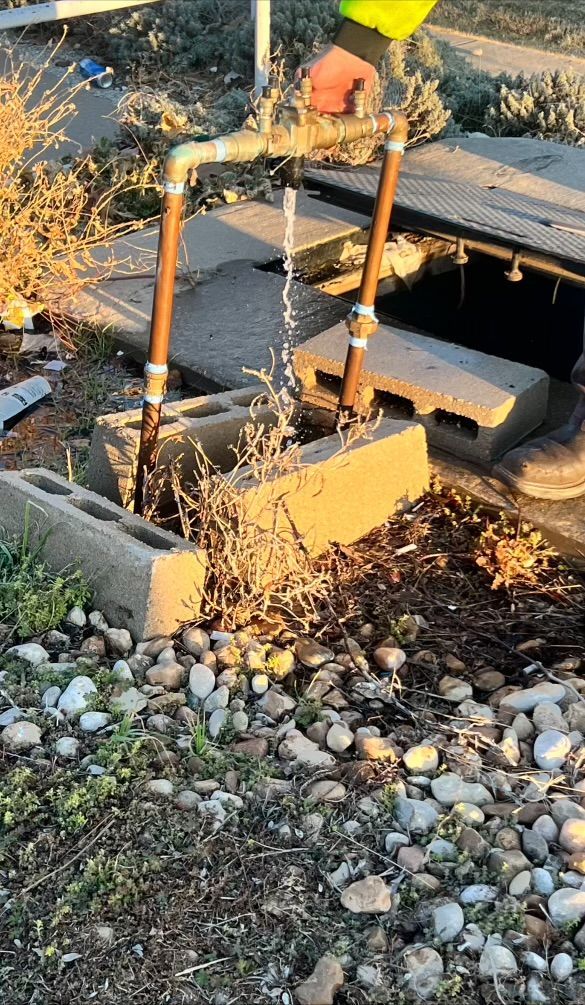 Water flows from exposed copper pipes set in cinder blocks outdoors.