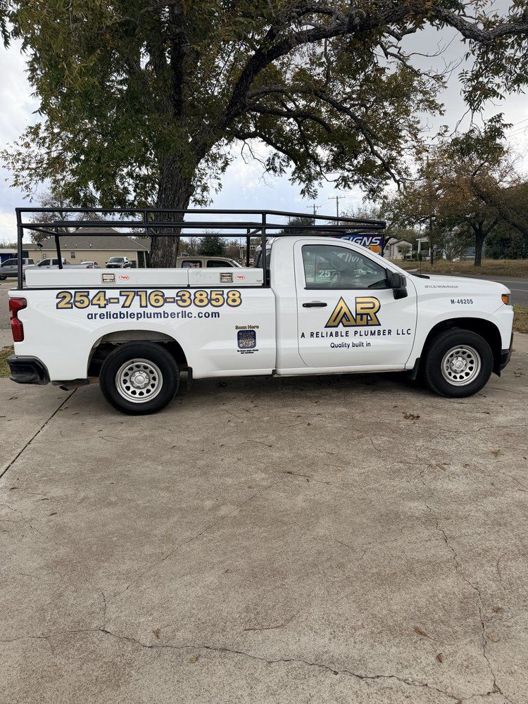 White work truck with black overhead rack and company logo parked on concrete.