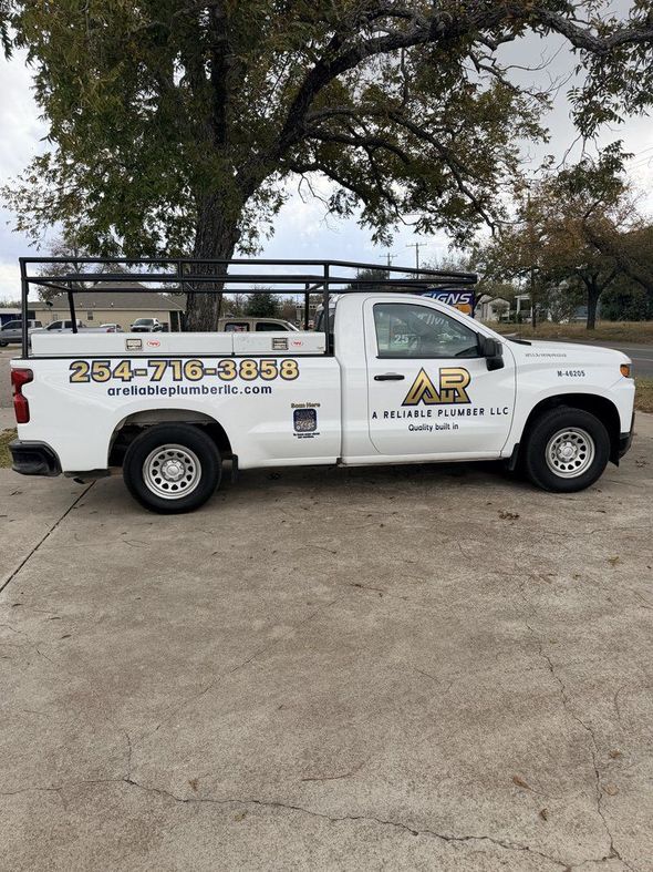 White work truck with black overhead rack and company logo, parked on concrete.