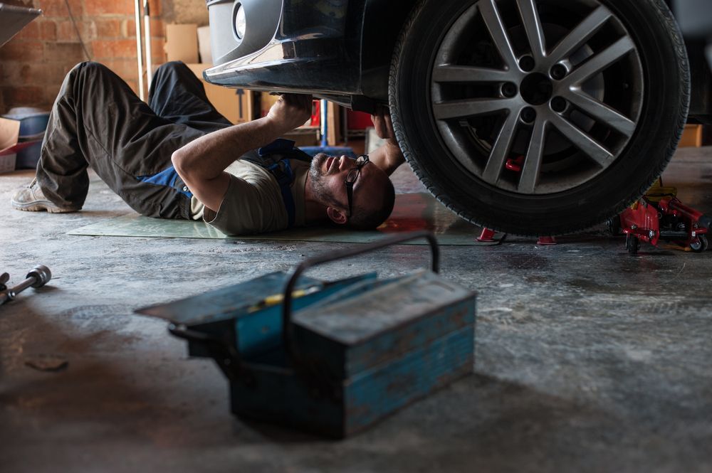 A Man is Laying on the Ground Working on a Car in a Garage — Turbo's Tyres In Humpty Doo, NT