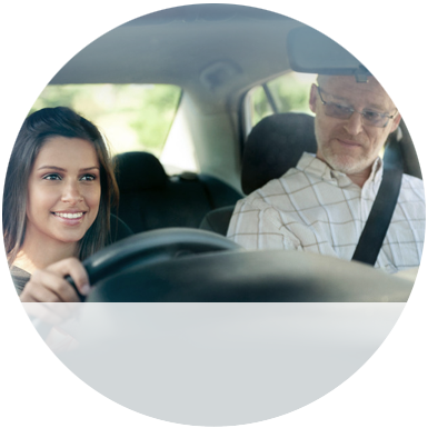 A girl driving, being watched by a man