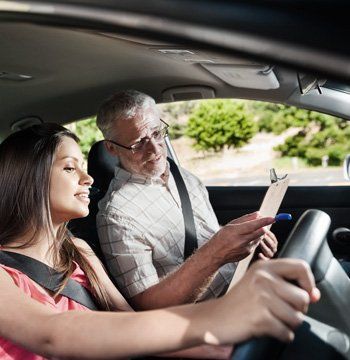 A man with a clipboard explaining something about a car to a young girl