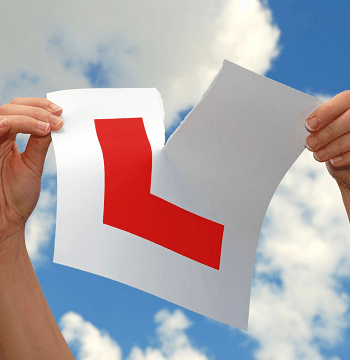 A learner plate being torn in half